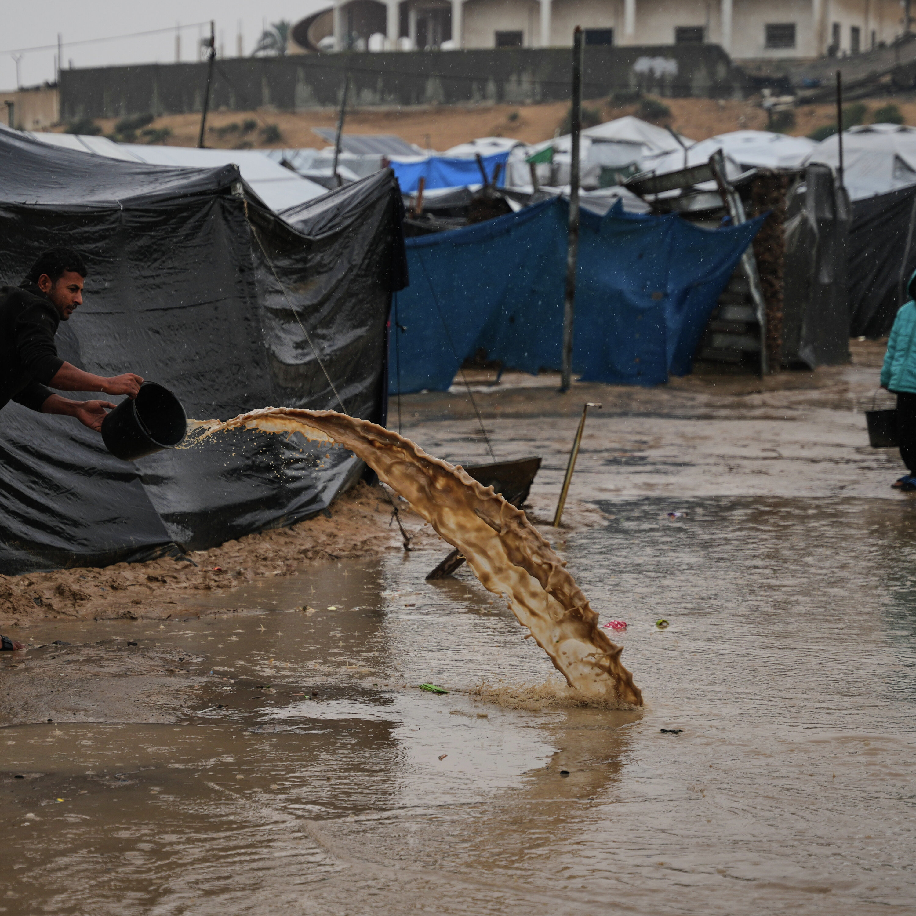 Storm worsens living conditions: A families dig trenches to keep water out of tents Storm worsens living conditions: A families dig trenches to keep water out of tents
